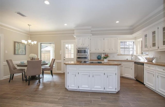 kitchen with white cabinets, appliances with stainless steel finishes, a chandelier, and pendant lighting