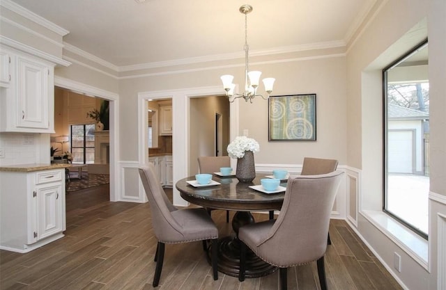 dining room featuring dark wood-type flooring, crown molding, and a chandelier