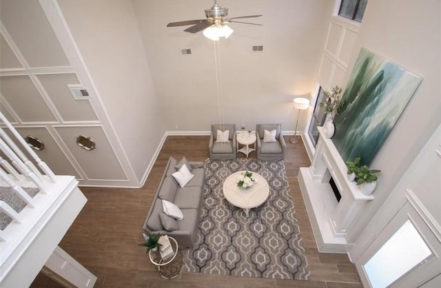 living room with ceiling fan, dark hardwood / wood-style flooring, and a towering ceiling