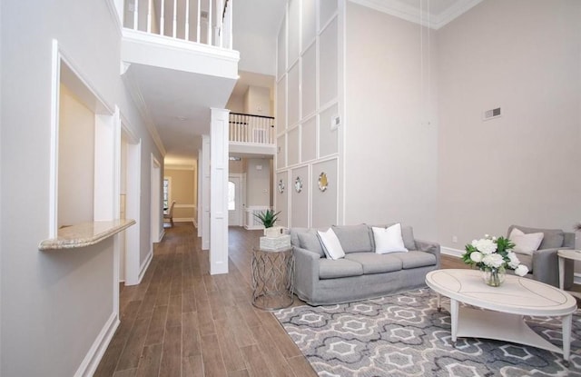 living room featuring a high ceiling, ornamental molding, and hardwood / wood-style floors