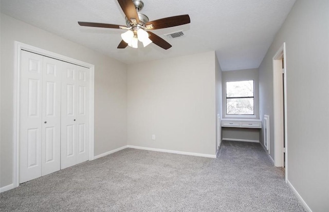 unfurnished bedroom with ceiling fan, a closet, and carpet