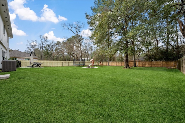 view of yard featuring central AC unit, a playground, and a trampoline