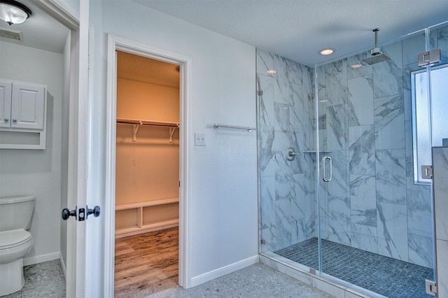 bathroom featuring toilet, a textured ceiling, and a shower with shower door