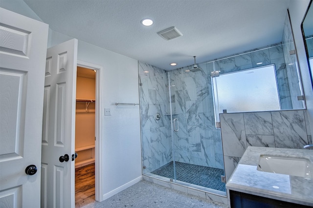 bathroom featuring a textured ceiling, an enclosed shower, and vanity