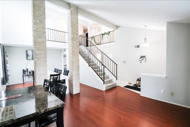 interior space featuring decorative columns, high vaulted ceiling, and dark hardwood / wood-style floors