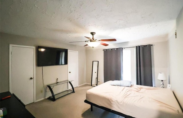 bedroom featuring a textured ceiling, light colored carpet, and ceiling fan