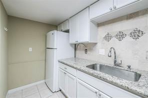 kitchen featuring sink, white cabinets, and light stone countertops