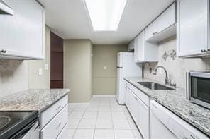 kitchen featuring sink, white cabinetry, light tile patterned floors, and light stone countertops