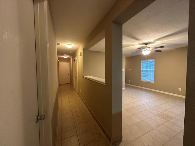 hallway with a textured ceiling and light tile patterned floors