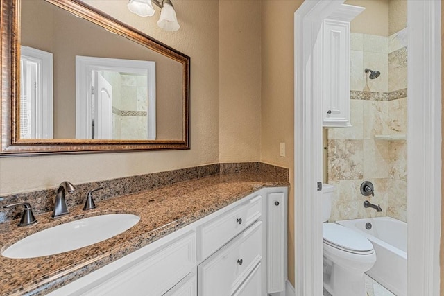 full bathroom with vanity, tiled shower / bath combo, and toilet