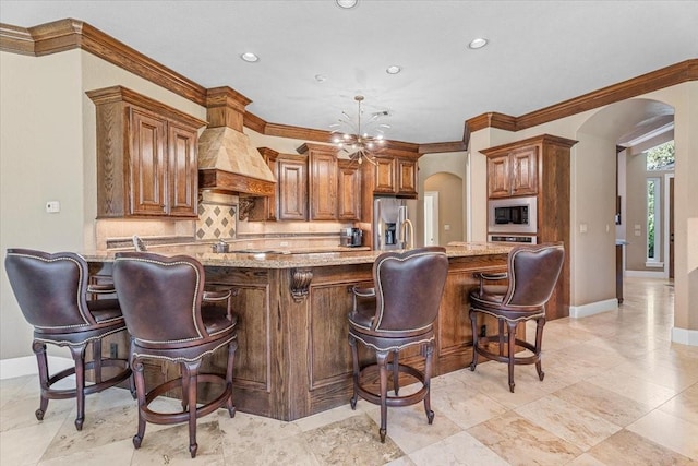 kitchen with light stone countertops, a kitchen island, custom range hood, and appliances with stainless steel finishes