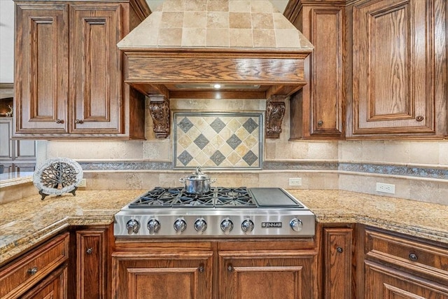 kitchen featuring stainless steel gas stovetop, tasteful backsplash, and light stone counters