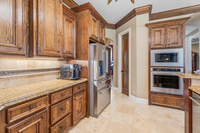 kitchen featuring light stone countertops, tasteful backsplash, ornamental molding, appliances with stainless steel finishes, and light tile patterned flooring