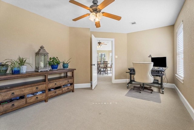 carpeted office space with ceiling fan and plenty of natural light