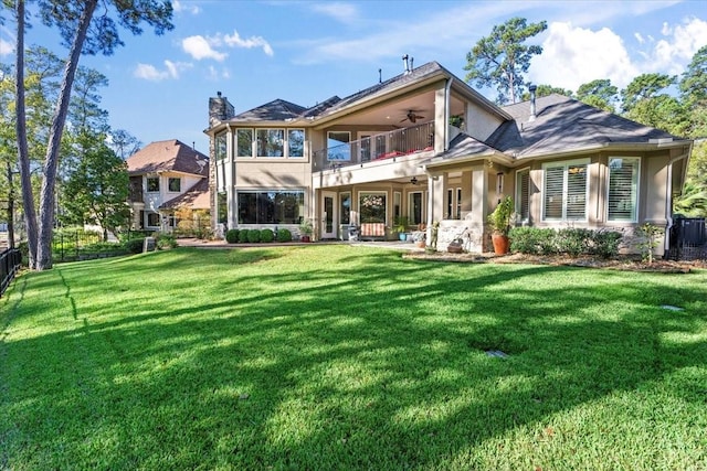 back of property featuring a yard, a balcony, and ceiling fan