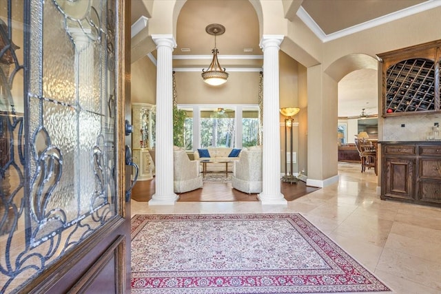 entryway featuring ornate columns, a high ceiling, ceiling fan, and ornamental molding