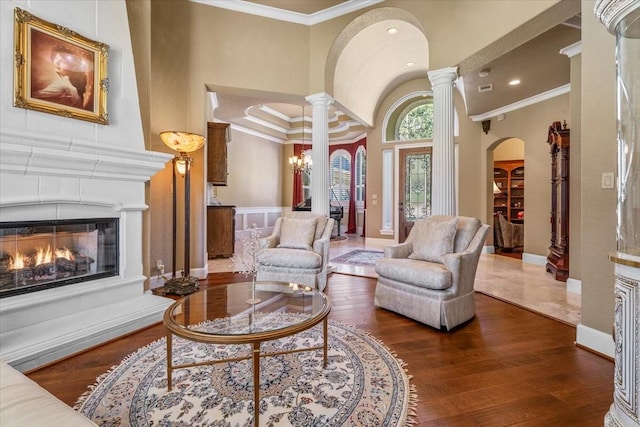 living room with ornamental molding, dark hardwood / wood-style flooring, a high ceiling, and ornate columns