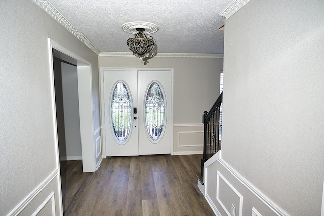 entryway with dark wood-type flooring, a textured ceiling, french doors, and ornamental molding