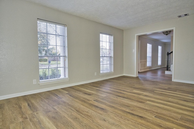 spare room with a healthy amount of sunlight, a textured ceiling, and hardwood / wood-style flooring