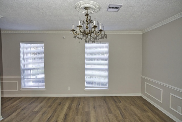 spare room with a textured ceiling, crown molding, a notable chandelier, and dark wood-type flooring