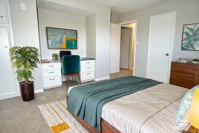 carpeted bedroom featuring built in desk