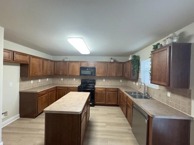 kitchen featuring black appliances, light hardwood / wood-style flooring, a center island, and sink