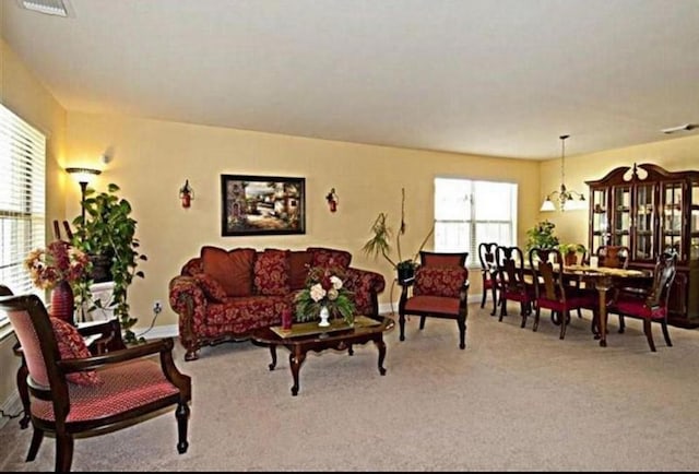 living room with carpet flooring, a chandelier, and a healthy amount of sunlight