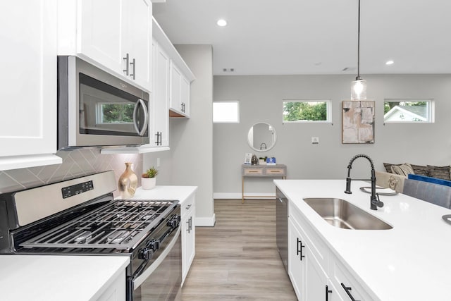 kitchen featuring pendant lighting, tasteful backsplash, white cabinetry, appliances with stainless steel finishes, and sink