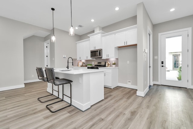 kitchen with white cabinetry, a kitchen island with sink, pendant lighting, and appliances with stainless steel finishes