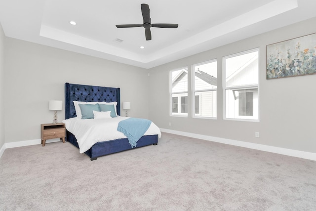 bedroom with a raised ceiling, carpet floors, and ceiling fan