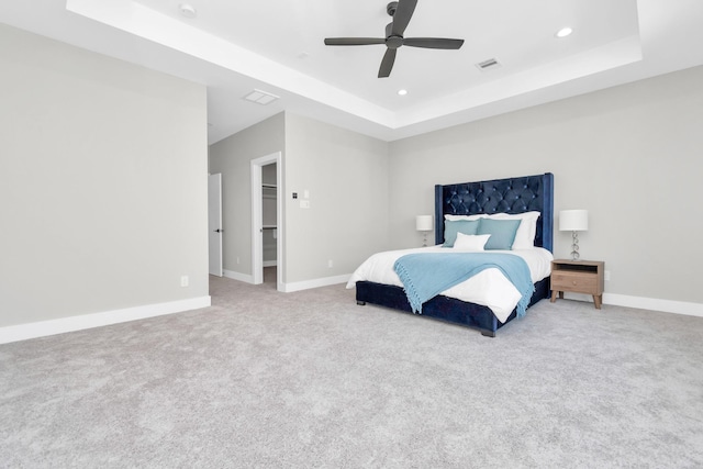 bedroom with ceiling fan, carpet, and a tray ceiling