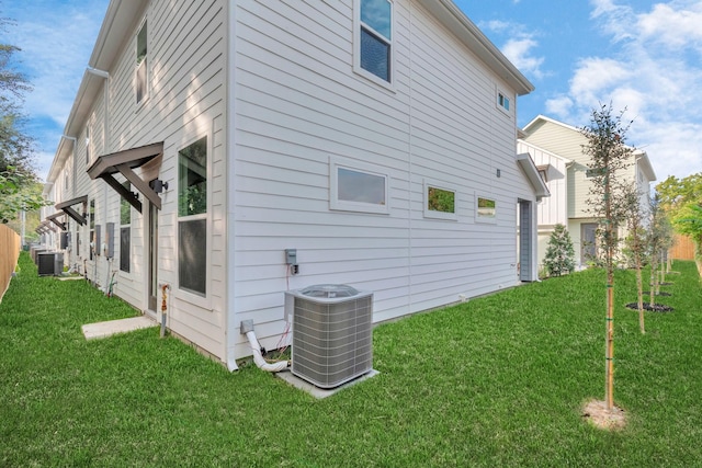 view of side of property with central AC and a lawn