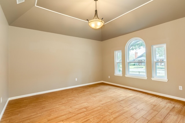 spare room with light wood-style floors, lofted ceiling, visible vents, and baseboards