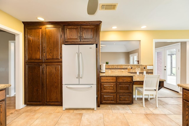 kitchen featuring light tile patterned floors, light stone counters, visible vents, and freestanding refrigerator