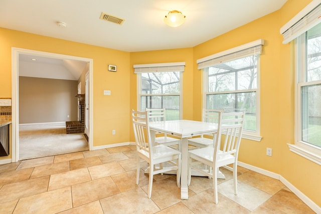dining area with baseboards, a wealth of natural light, visible vents, and a fireplace