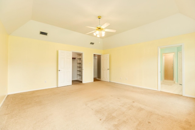 unfurnished bedroom with ceiling fan, connected bathroom, carpet flooring, lofted ceiling, and a walk in closet