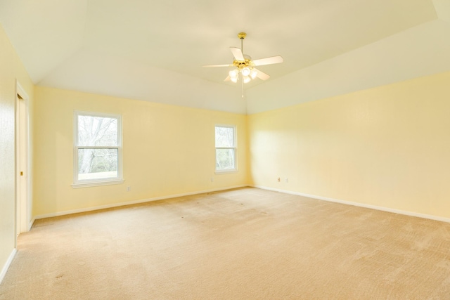 empty room featuring baseboards, lofted ceiling, and light colored carpet
