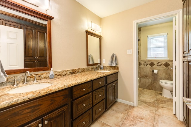 bathroom with toilet, vanity, and tile walls