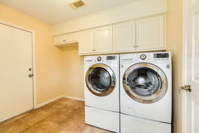 laundry area featuring visible vents, light tile patterned floors, washing machine and clothes dryer, baseboards, and cabinet space