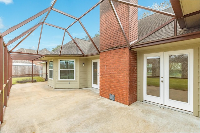 exterior space with french doors, a lanai, brick siding, a shingled roof, and a patio