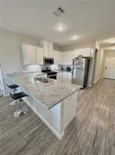 kitchen featuring sink, white cabinets, light stone counters, and appliances with stainless steel finishes