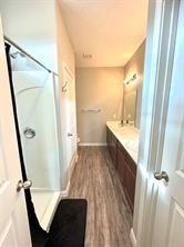 bathroom featuring hardwood / wood-style floors, a shower, and vanity