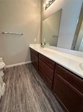 bathroom with toilet, vanity, and hardwood / wood-style floors