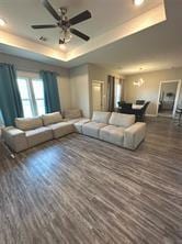 living room with ceiling fan, a tray ceiling, and dark hardwood / wood-style floors