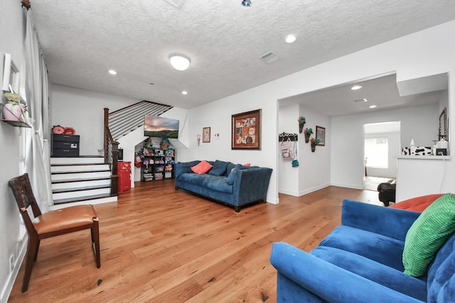 living room with a textured ceiling and light hardwood / wood-style floors