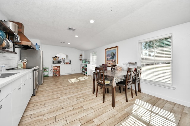 dining area featuring lofted ceiling and a textured ceiling