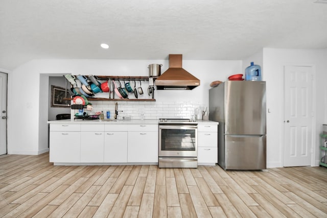 kitchen featuring island exhaust hood, stainless steel appliances, sink, light hardwood / wood-style flooring, and white cabinetry