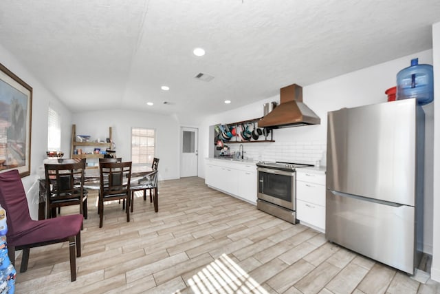 kitchen featuring tasteful backsplash, island exhaust hood, appliances with stainless steel finishes, white cabinets, and sink