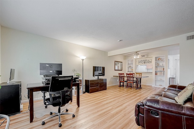 office with ceiling fan, hardwood / wood-style floors, a textured ceiling, and built in shelves