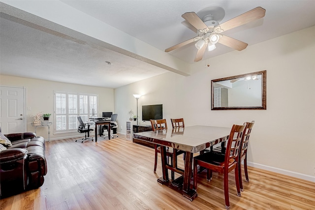 dining area with ceiling fan, light wood-type flooring, and beam ceiling